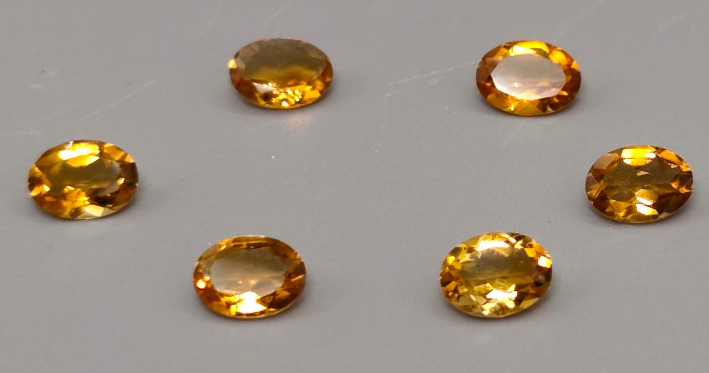 Six oval-shaped yellow gemstones on a gray background