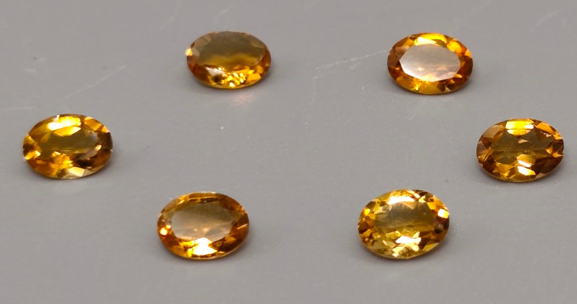 Six oval-shaped yellow gemstones on a gray background
