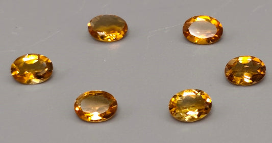 Six oval-shaped yellow gemstones on a gray background